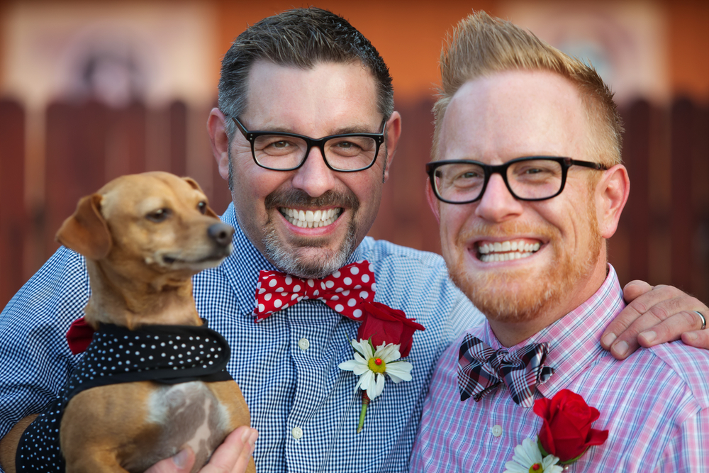 Outdoor marriage ceremony for male gay couple with dog at wedding ceremony.