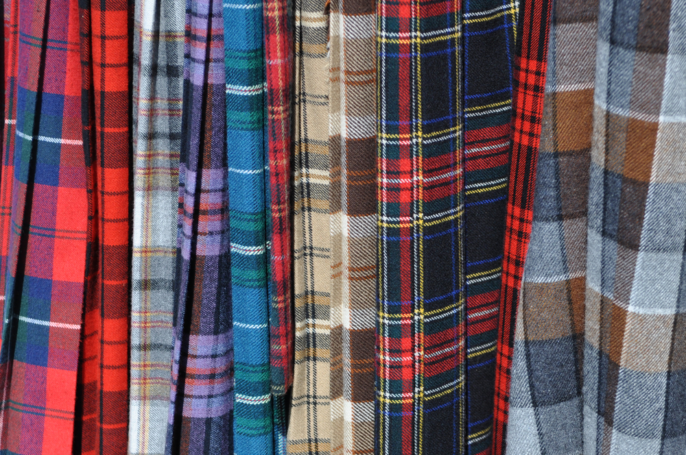 Scottish Kilts linned up to show off the different weaves and patterns. An assortment of colourful Scottish tartan kilts.