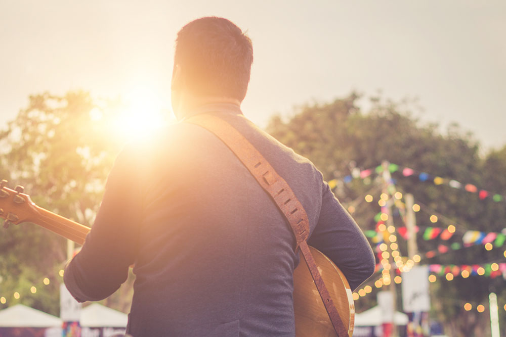 A man facing the audience playing guitar with his back to us.