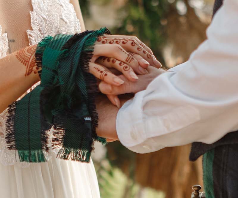 A man and woman in Scottish dress with handfasting ceremony.