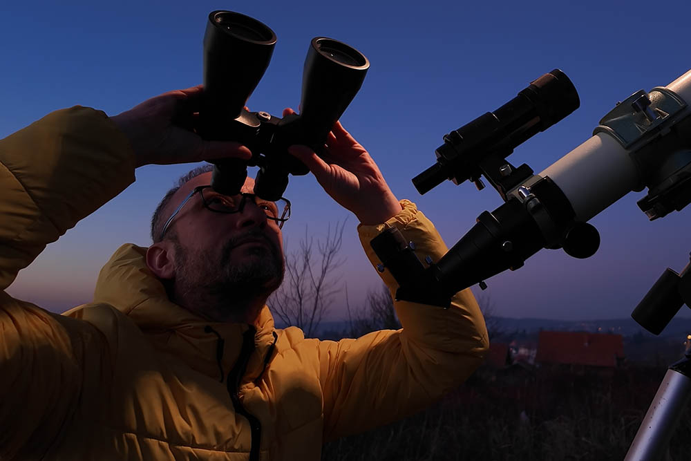 A man stargazing with binoculars.