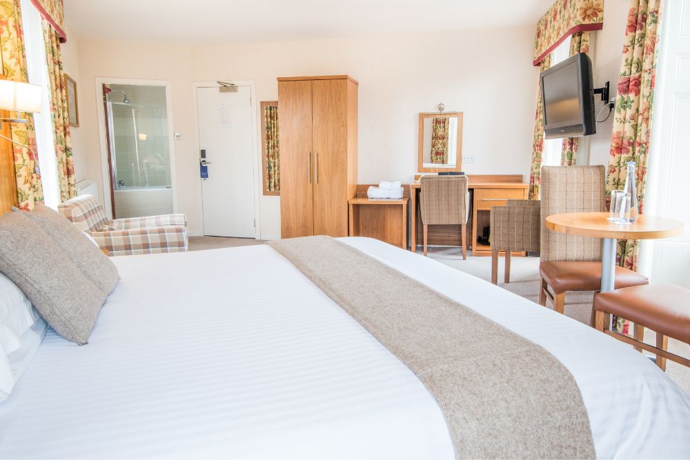 View of the superior bedroom at Mackays Hotel in wick, featuring the bed and desk to work at. 
