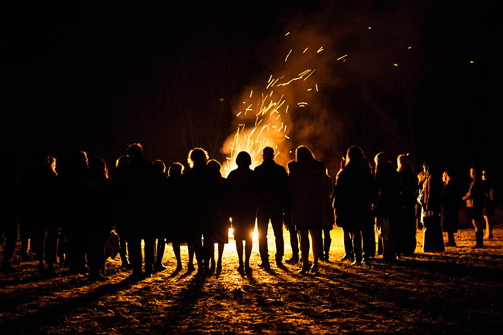People gathered around a bonfire at night.