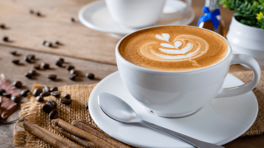 Coffee in a white cup with coffee beans nearby.